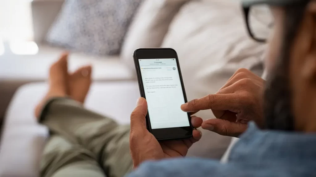 Pessoa usando celular para consulta restituição IRPF 2025 no aplicativo da Receita Federal.