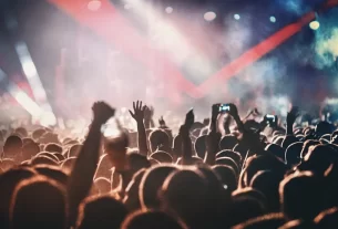 Multidão de fãs com pulseiras luminosas no show do Coldplay no Maracanã, Rio de Janeiro, em 2023.