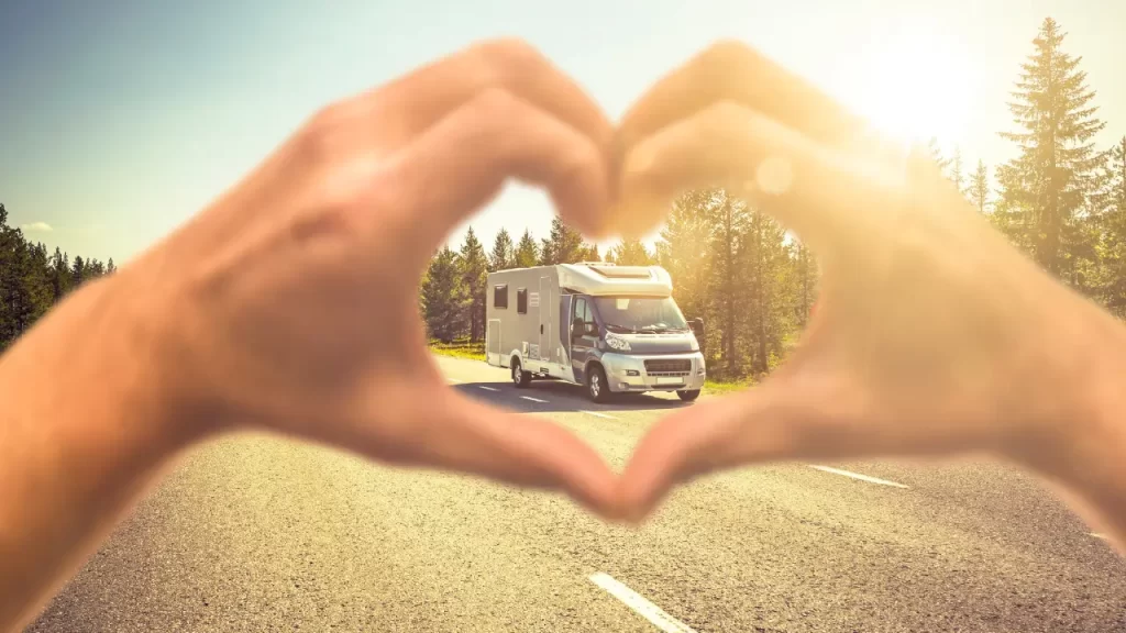 Motorhome solar viajando por uma estrada ao pôr do sol, simbolizando aventura e liberdade.