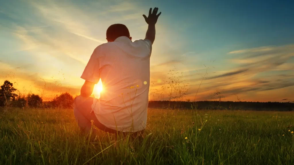 Nascer do sol com pessoa orando.