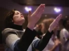 Pessoa ouvindo playlist devocional em culto, ideal para 2025.