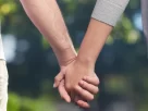 Duas mãos entrelaçadas contra um fundo neutro, representando confiança e vínculo em um relacionamento aberto.