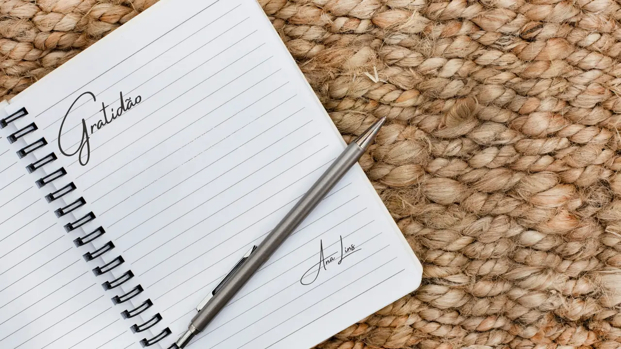 Um diário aberto com a palavra "Gratidão" escrita em uma mesa de madeira.