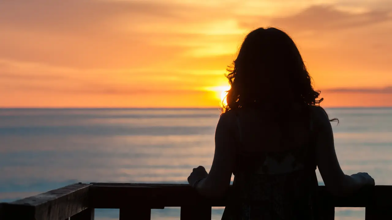Pessoa no topo de uma colina olhando o nascer do sol, simbolizando a clareza após a jornada de autoconhecimento.