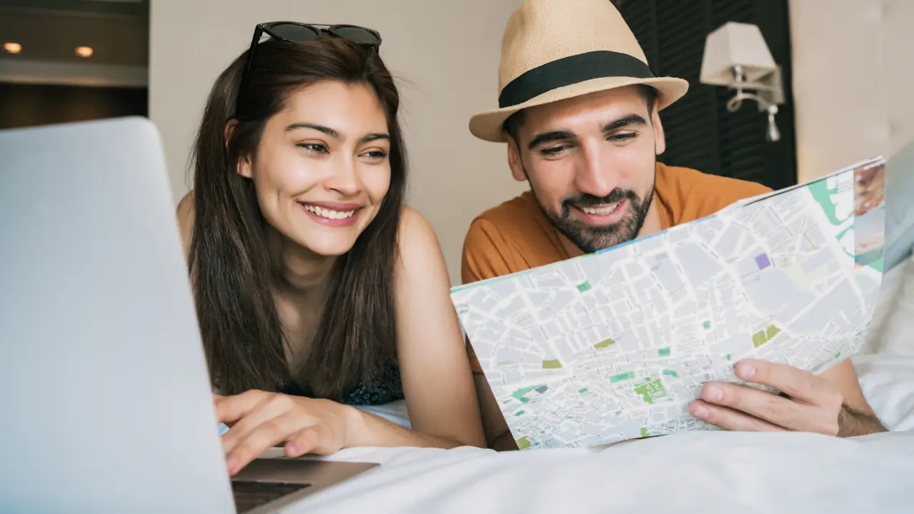 Casal sorrindo em frente a um mapa, planejando as férias em casal com tranquilidade e conexão.