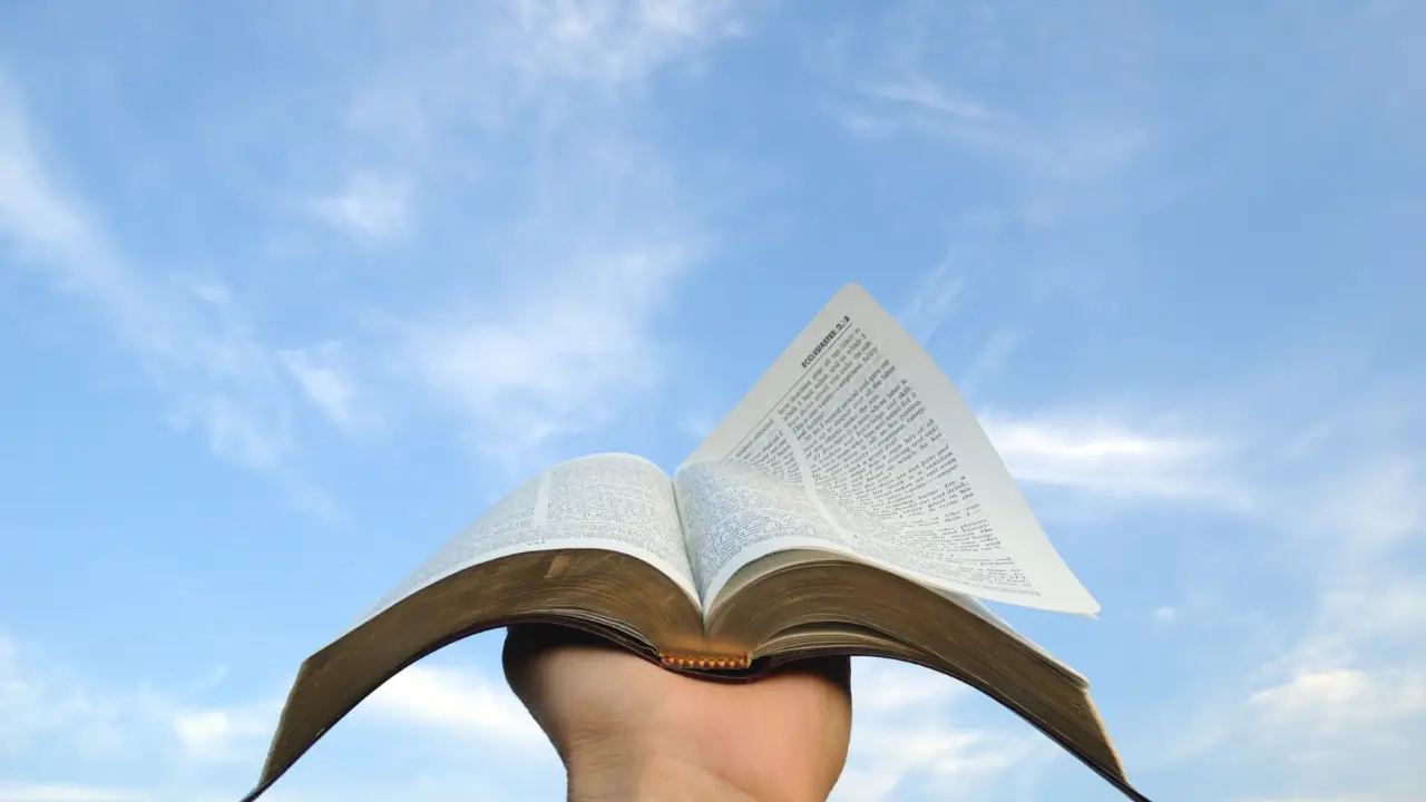 Mãos segurando a bíblia aberta