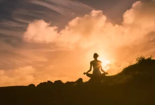 Mulher meditando em frente a uma paisagem natural exuberante, representando um dos destinos espirituais.