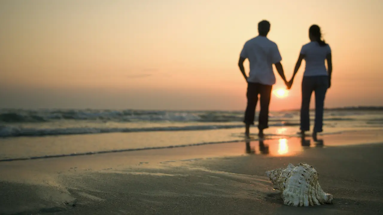 Casal de mãos dadas olhando para o horizonte, simbolizando um relacionamento com propósito e visão de futuro.